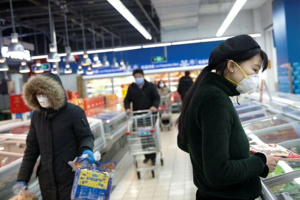 Personas con mascarillas buscando productos en un supermercado de Beijing, China. Foto: Reuters / Carlos García Rawlins.
